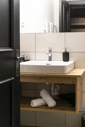 A bathroom with a white sink, a wooden countertop, and a mirror above it. - Basur (Flirsch)