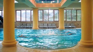 An indoor swimming pool with clear water, surrounded by yellow columns, and a ceiling with a starry light fixture. - Eklips Hotel (Farkë)