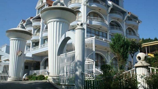 A multi-story building with balconies, large columns, and a gated entrance. - Eklips Hotel (Farkë)