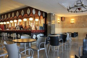 A restaurant with a bar area, multiple tables, and chairs. - Hotel Calella by Beatriz Hoteles (Calella)