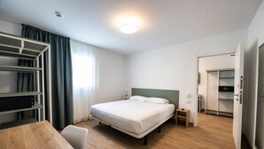 A hotel room with a bed, bedside table, wardrobe, and a desk with a chair. - Fragata Hotel (Calella)