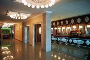 A hotel lobby with a reception desk, a bar area with stools, and a wall with clocks. - Hotel Calella by Beatriz Hoteles (Calella)