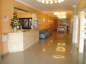A hotel reception area with a reception desk, seating area, and a chandelier. - Hotel Calella by Beatriz Hoteles (Calella)