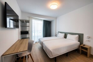 A hotel room with a bed, a desk, a chair, a wardrobe, and a window with curtains. - Hotel Calella by Beatriz Hoteles (Calella)