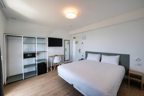 Une chambre d’hôtel comprenant un lit, un bureau, une chaise, une armoire et un téléviseur.