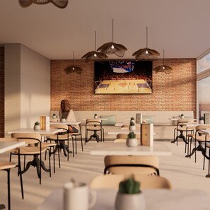 A modern cafe with brick walls, multiple tables, chairs, hanging lights, and a large TV screen displaying a basketball game. - Hotel Calella by Beatriz Hoteles (Calella)
