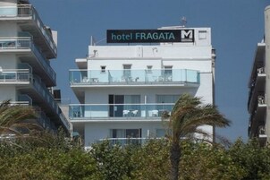 Un hotel de varios pisos llamado 'hotel FRAGATA' con balcones y mesas al aire libre.