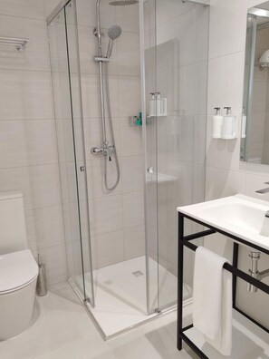 A modern bathroom with a glass-enclosed shower, a white sink, and a toilet. - Hotel Calella by Beatriz Hoteles (Calella)