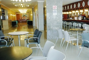 Un vestíbulo de hotel con mostrador de recepción, zona de estar y bar.