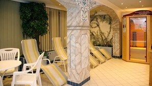 A spa area with white plastic chairs, a marble column, and a reception desk. - Hotel Schneeberger (Wildschönau)
