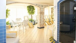 A spa area with seating, a massage table, and a shower area. - Hotel Schneeberger (Wildschönau)