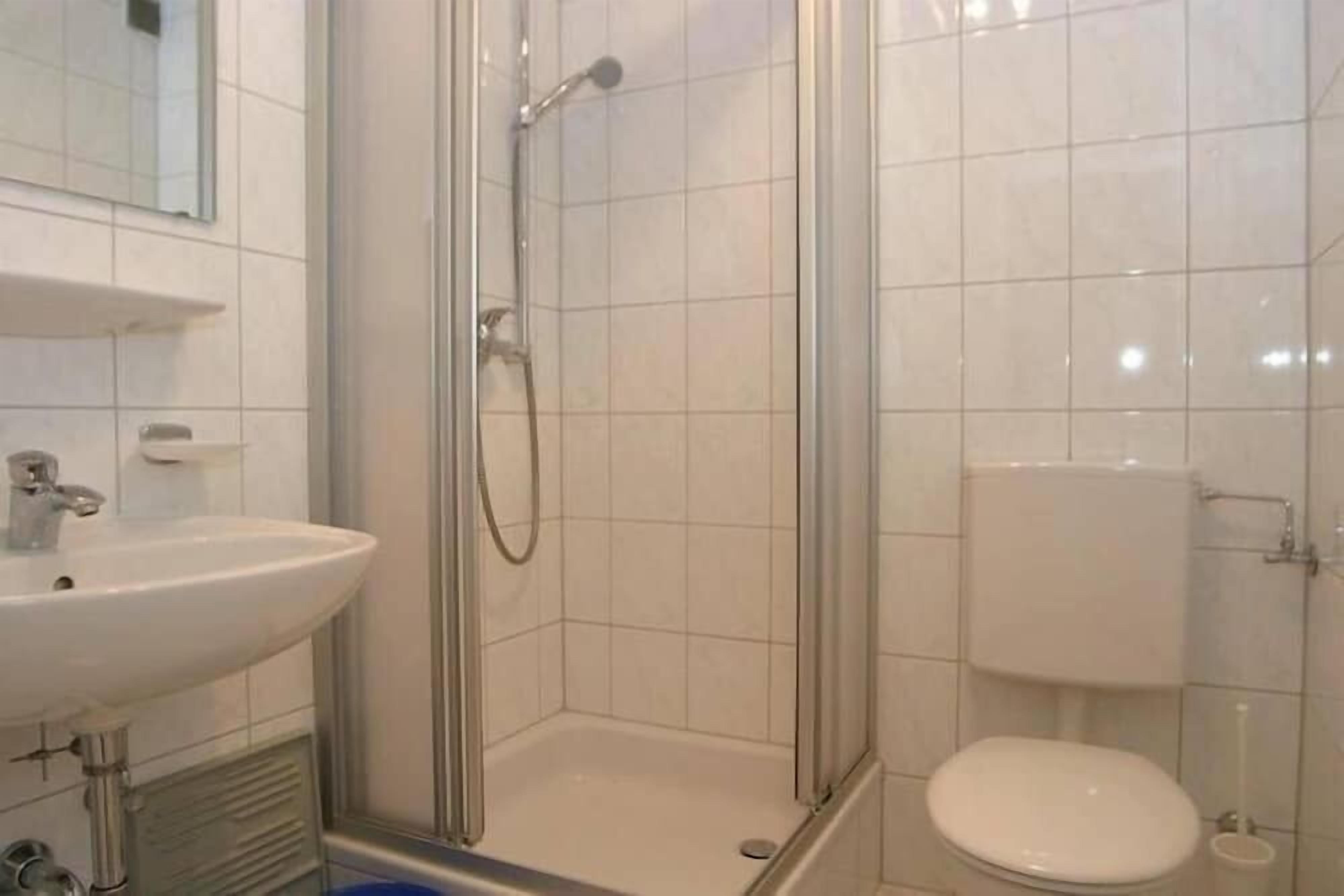A bathroom with a glass-enclosed shower, a sink, and a toilet.