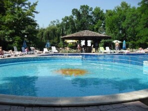 A swimming pool with lounge chairs and umbrellas, surrounded by trees. - Regina (Nessebar)