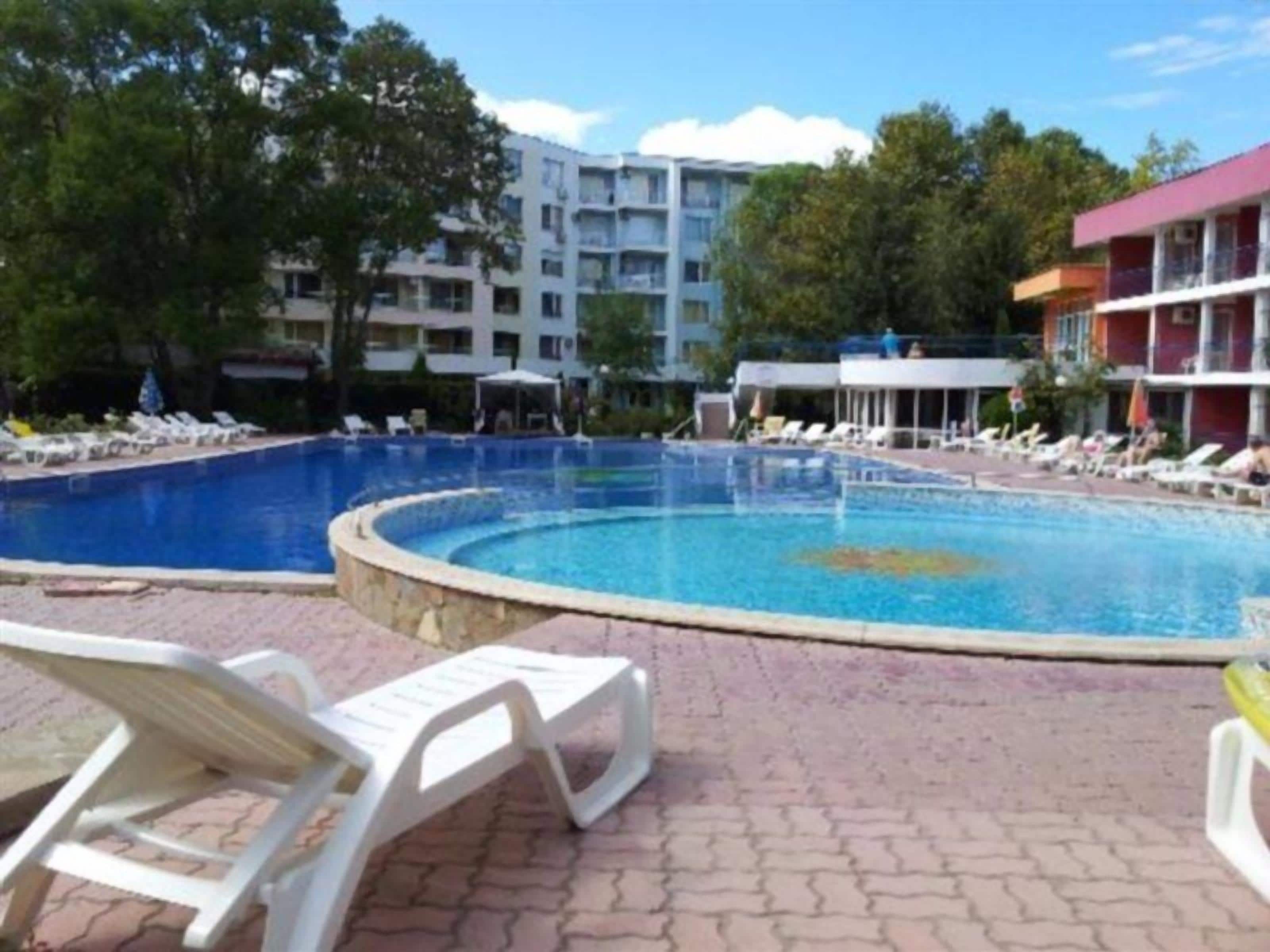 A swimming pool with lounge chairs and a brick walkway.