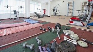 Un gimnasio con diferentes equipos de ejercicio, colchonetas y pesas.