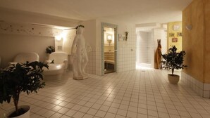 A hotel lobby with a tiled floor, a statue, a reception desk, and potted plants. - Hotel Tia Monte (Kaunertal)