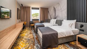 Quarto de hotel moderno com duas camas, uma escrivaninha e uma janela grande com vista para a cidade.