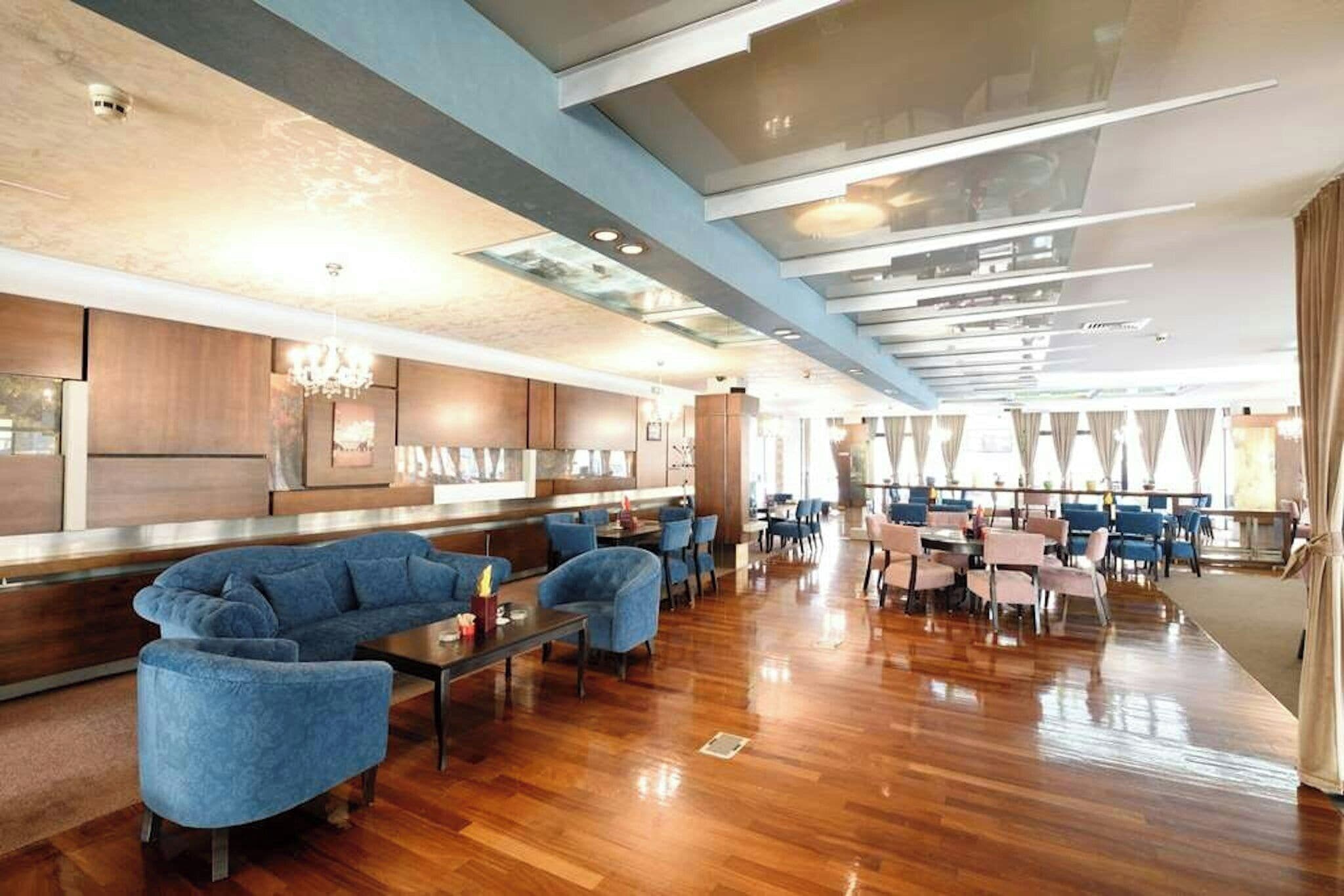 Un moderno vestíbulo de hotel con zona de estar, suelo de madera y un gran ventanal.