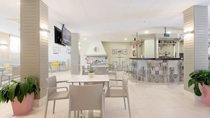 Un lobby moderno de hotel con zona de comedor, cocina y bar.