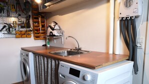 A compact laundry area with a washing machine, a sink, and a drying rack. - Rose Cottage 15m2 Tórshavn with Parking (Hoyvík)
