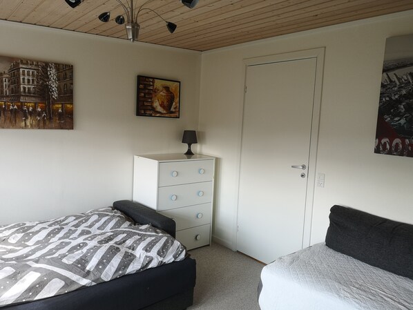 Un dormitorio con cama, cómoda y puerta.
