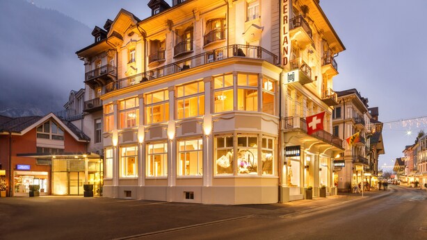 Un hotel de varios pisos con amplias ventanas, balcones y un cartel que indica que es un hotel.