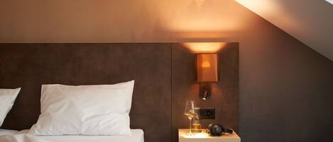 Een moderne slaapkamer met een bed, nachtkastje, lamp en een boek.