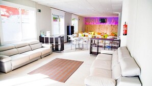 A modern hotel lobby with a seating area, a reception desk, and a dining area. - Sun Beach (Lloret de Mar)