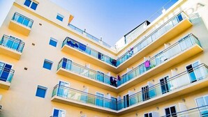 A multi-story building with balconies, each with glass railings and a yellow facade. - Sun Beach (Lloret de Mar)