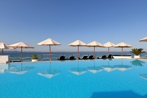 A clear blue pool with lounge chairs and umbrellas, overlooking a body of water. - Sunnyside Apartments Petrcane (Zadar)