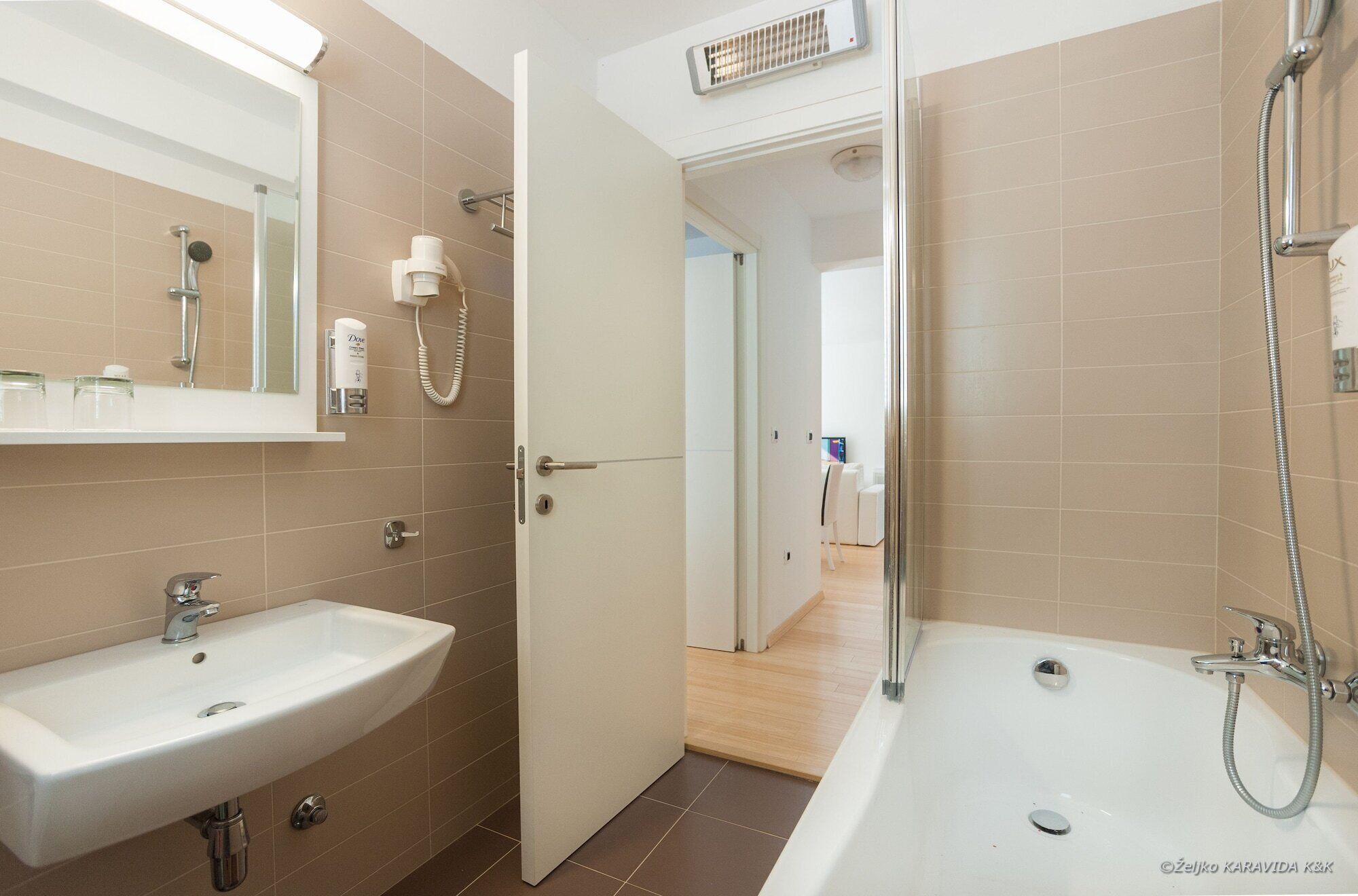 A modern bathroom with a sink, mirror, shower, and toilet.