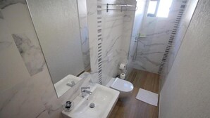 Un baño con lavamanos blanco, inodoro y zona de ducha.
