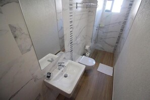 A bathroom with a white sink, a toilet, and a shower area. - Saranda International Hotel (Sarandë)