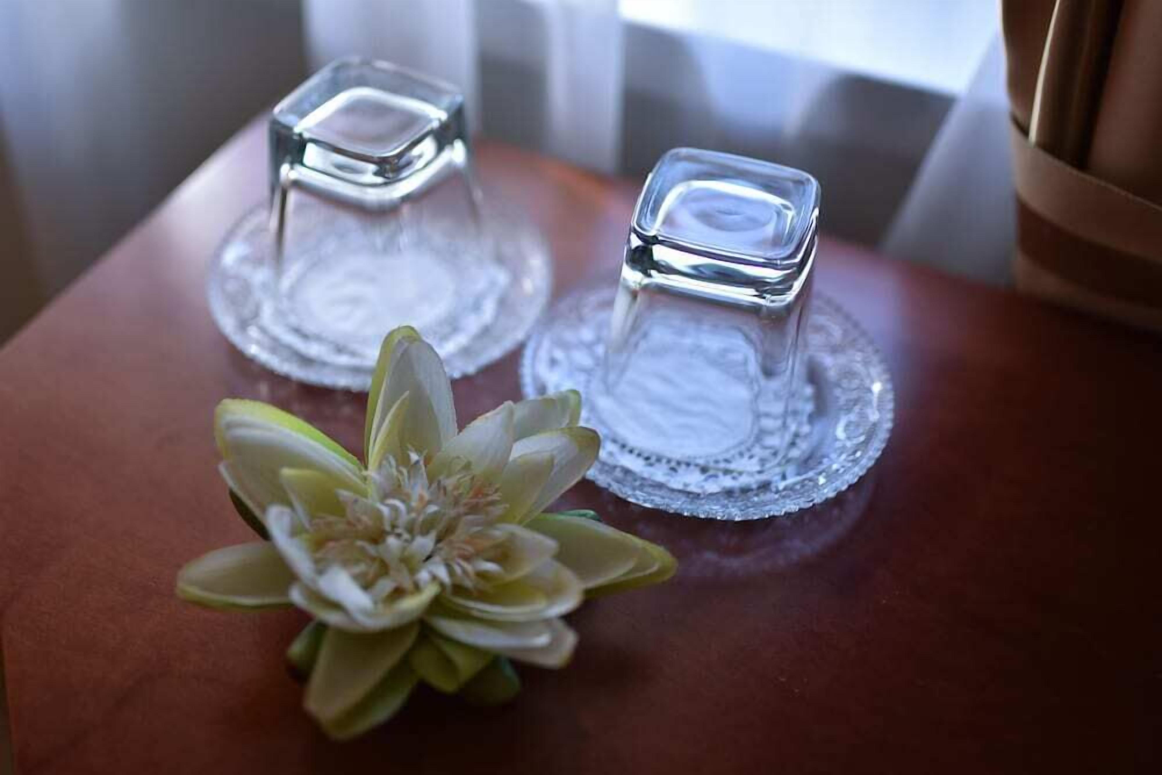 Two clear glass candle holders on a wooden surface with a decorative glass plate underneath.