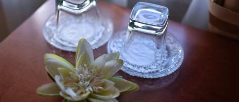 Two clear glass candle holders on a wooden surface with a decorative glass plate underneath.