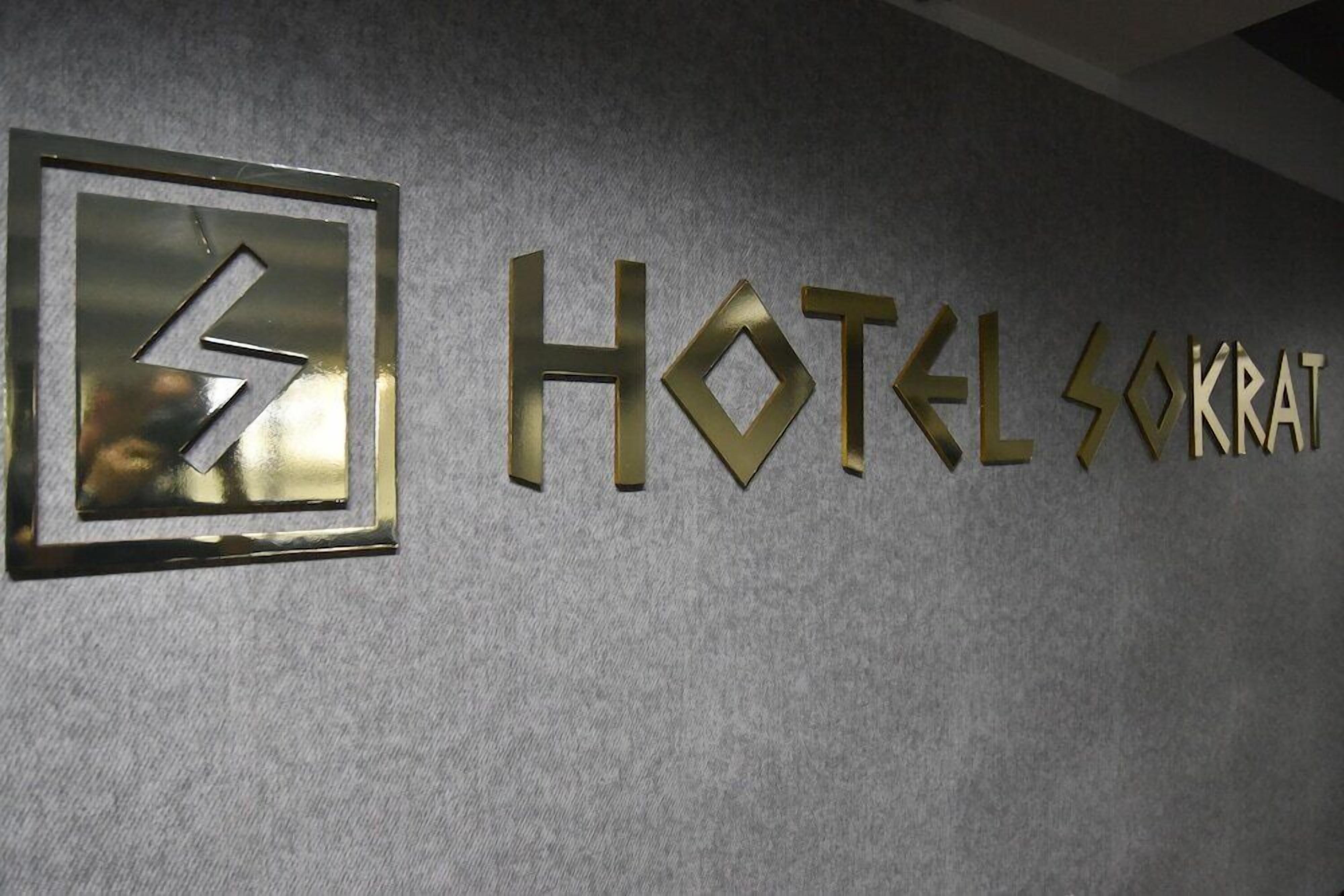 A hotel sign with the name "HOTEL SOKRAT" and a logo with a stylized 'S' and 'K' design.