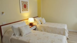 A hotel room with two beds, a nightstand with a lamp, and a decorative wall piece. - Sokrat Hotel (Tirana)