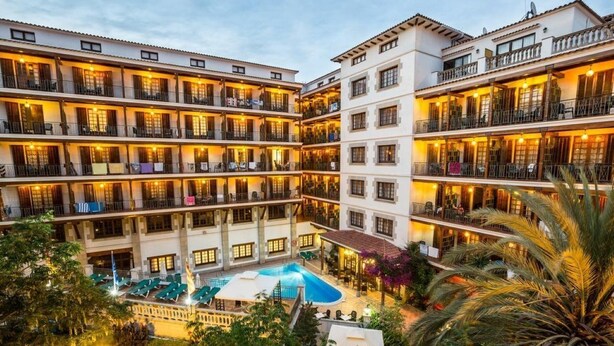 Un hotel de varios pisos con balcones, un patio central y una piscina.