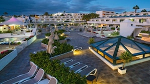 A rooftop pool area with sun loungers, umbrellas, and a glass-enclosed lounge. - Relaxia Lanzaplaya (Tías)