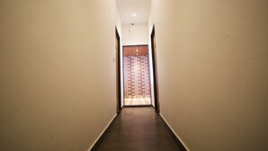 A narrow, well-lit hallway with a wooden floor and a brick wall at the end. - Hotel Park View (Bhopal)