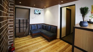 A modern living room with a wooden floor, a sectional sofa, a TV mounted on the wall, and a small potted plant on a table. - Hotel Park View (Bhopal)