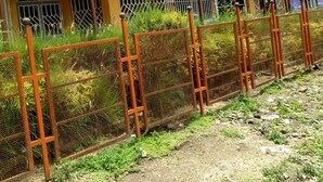A building with a green sign indicating a hotel, a fenced area with a gate, and a sign for a motor spares shop. - Golden Bay Hotel (Naivasha)