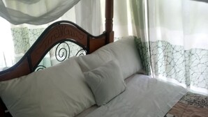 A bed with a wooden headboard, white pillows, and a patterned bedspread. - Golden Bay Hotel (Naivasha)