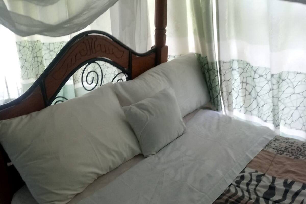 Un lit avec une tête de lit en bois, des oreillers blancs et une couvre-lit à motifs.