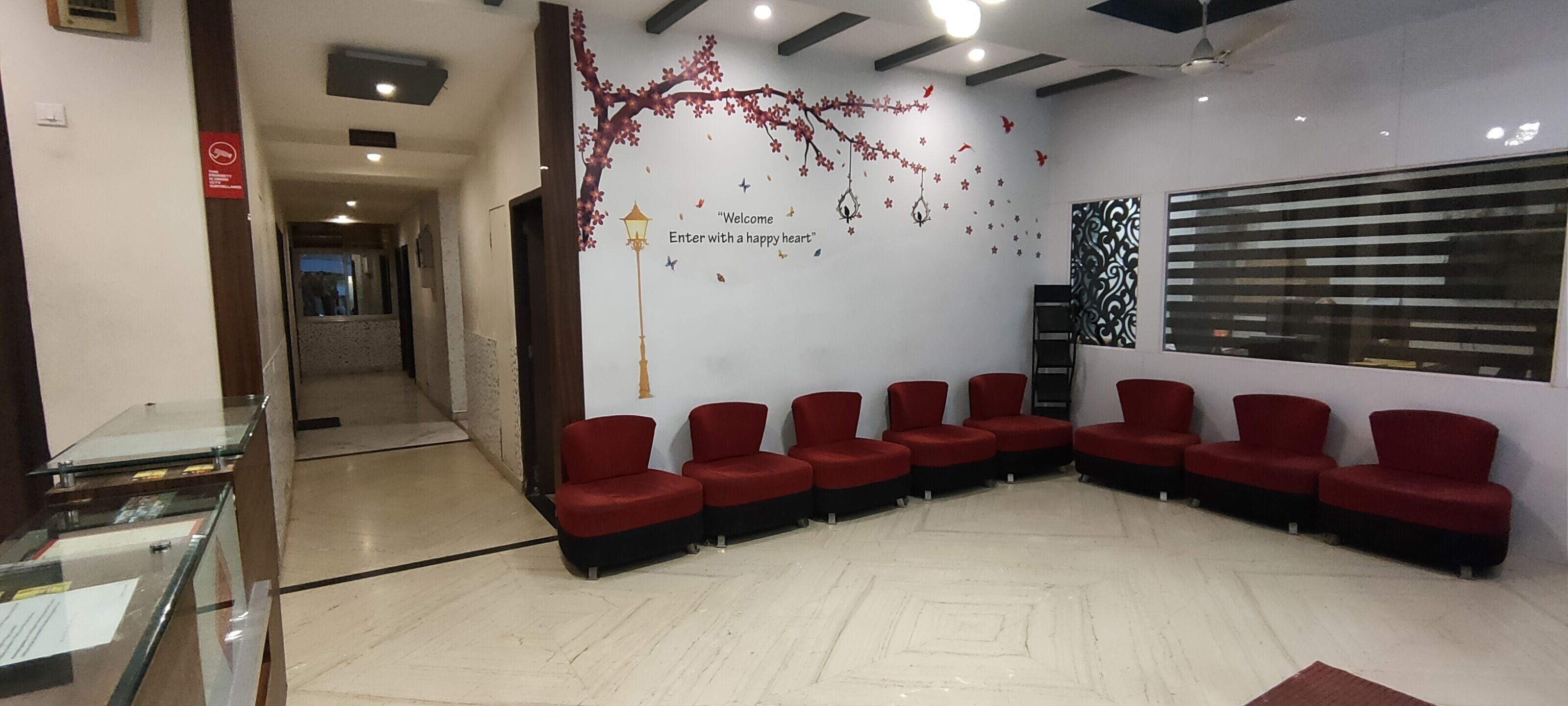 A reception area with a seating area, a glass display case, and a wall with a decorative tree and stars.
