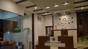 Un área de recepción con un mostrador de madera, una pared con separador de vidrio y decoración de círculos y motivos solares.