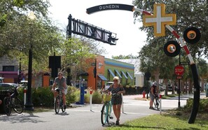 A street scene with a railway crossing sign, a stop sign, and a building with a colorful facade.