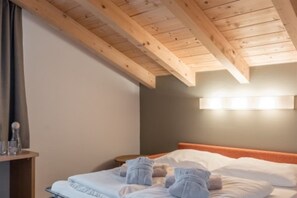 A hotel room with a wooden ceiling, a bed with white linens, and a bedside table with a lamp. - Hotel Tyrolerhof (Soelden)