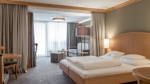 Quarto de hotel com cama, escrivaninha, cadeira e abajur.