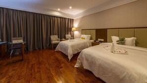 A hotel room with two beds, a desk, a chair, a lamp, and a teddy bear on one bed. - Linzhen Hotel (Shanghai)